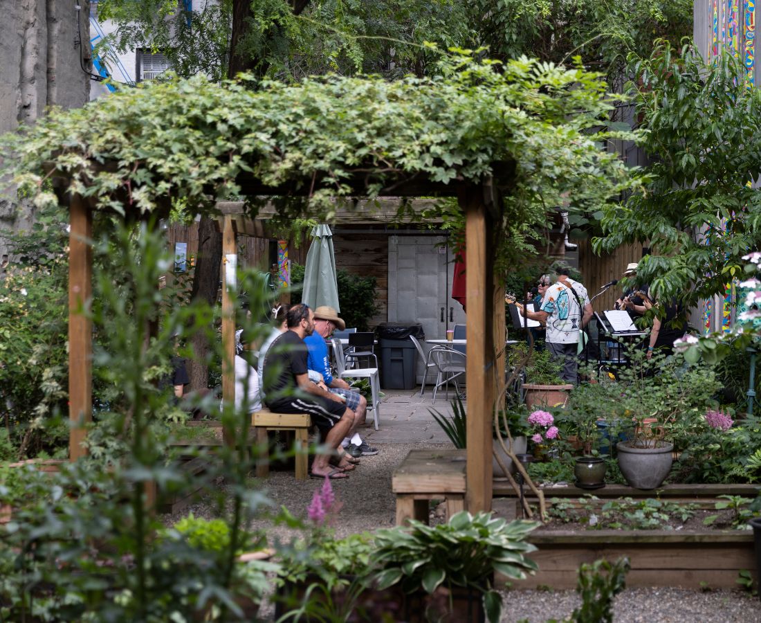 People sitting in a flourishing garden watching musicians play