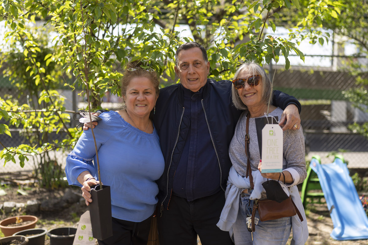 people holding saplings in a garden and smiling at the camera