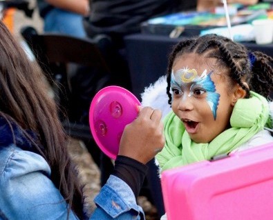 A girl smiles as she gets her face painted