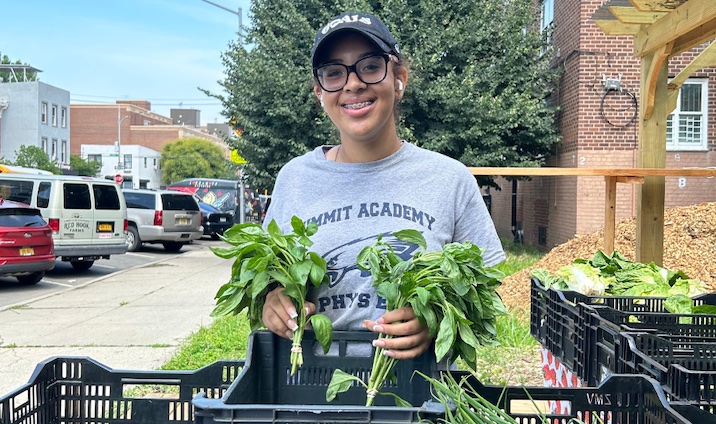 person holds produce smiling to camera