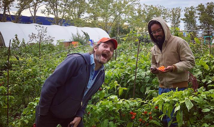 people standing in garden holding produce and smiling